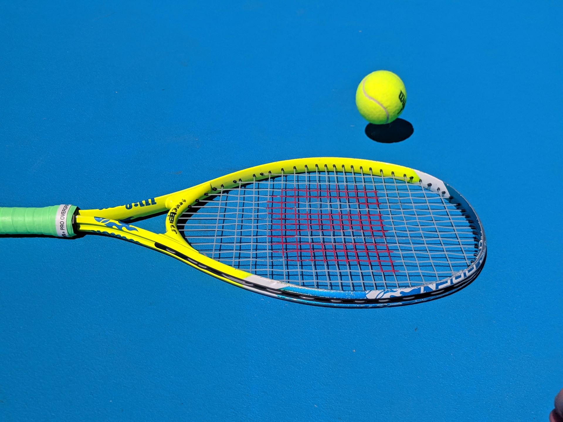 Tennis racket and ball on court.